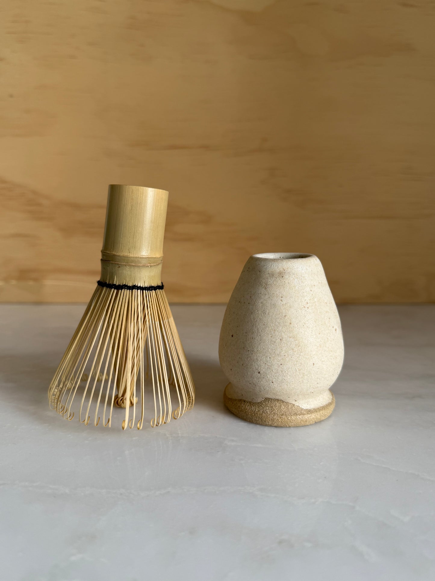 Matcha whisk holder glazed and white next to a Matcha whisk