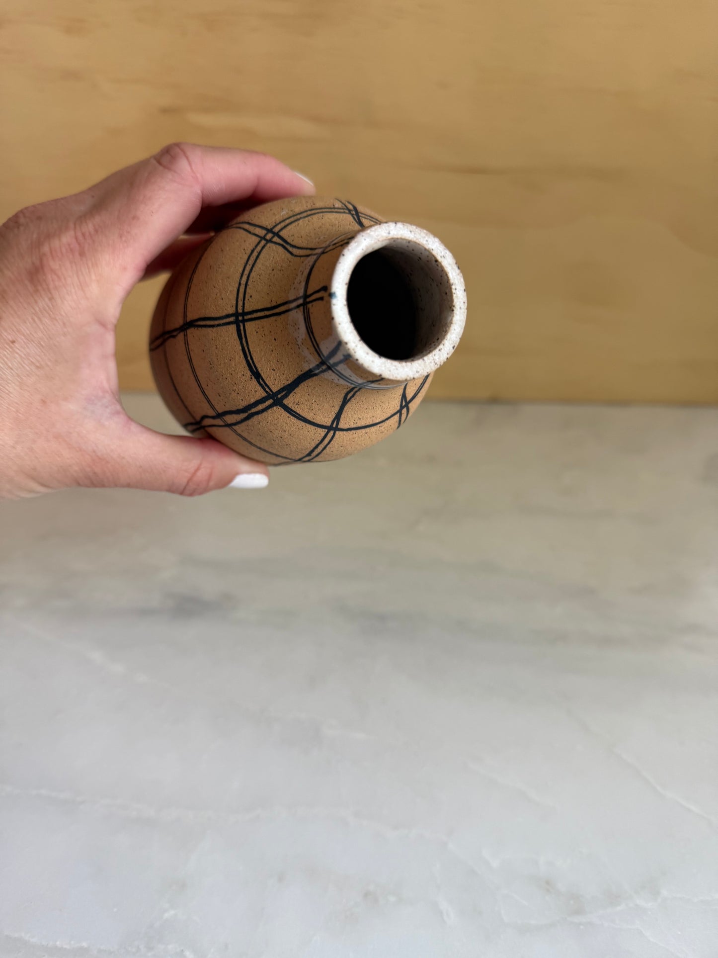 Hand holding handmade ceramic base showing bottleneck top