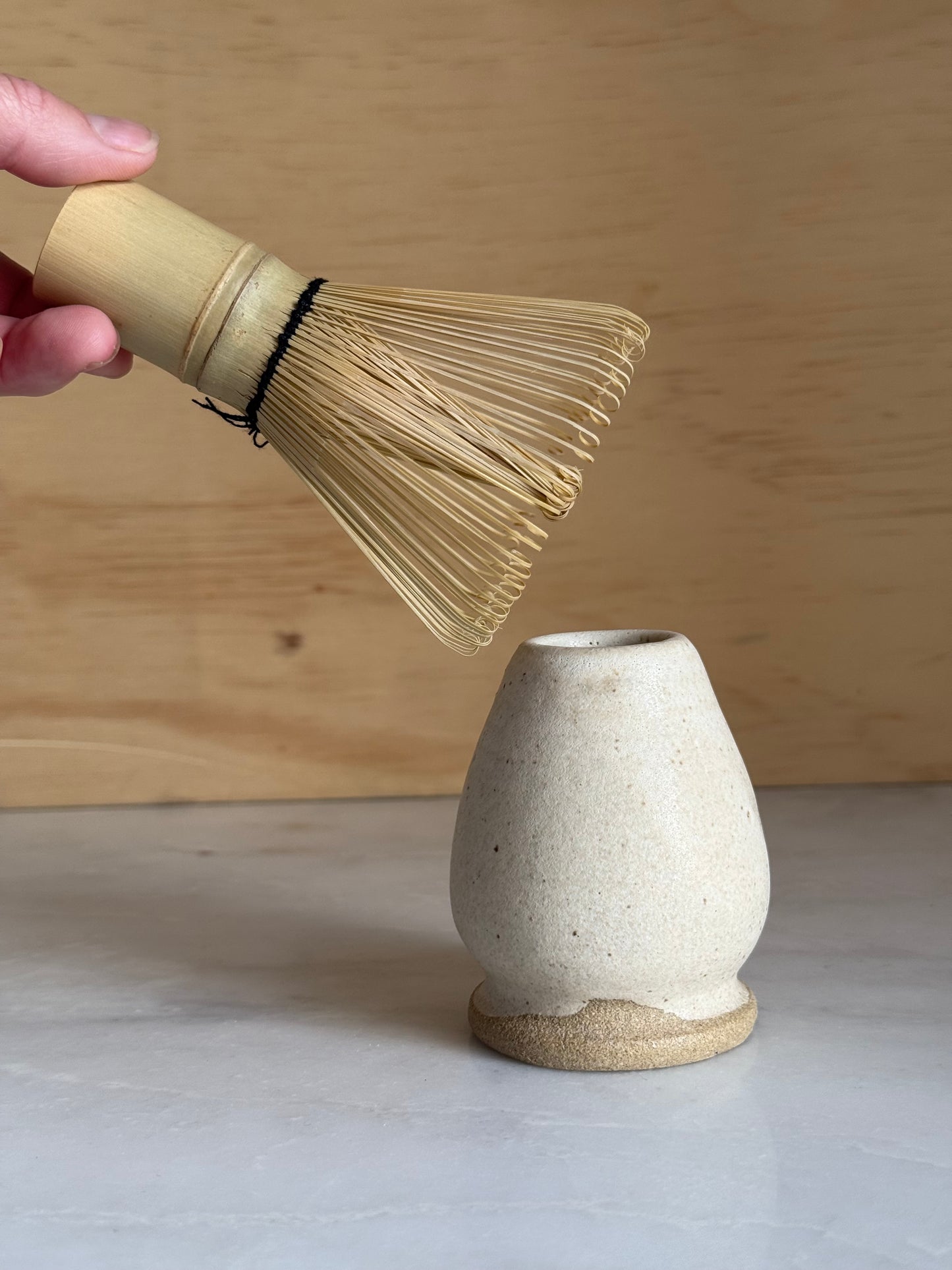 Matcha whisk holder glazed in white next to a Matcha whisk