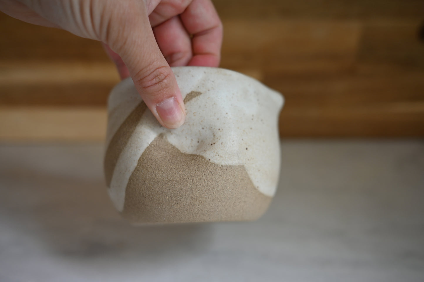 Person holding matcha bowl showing the dimple on the side, glazed in white