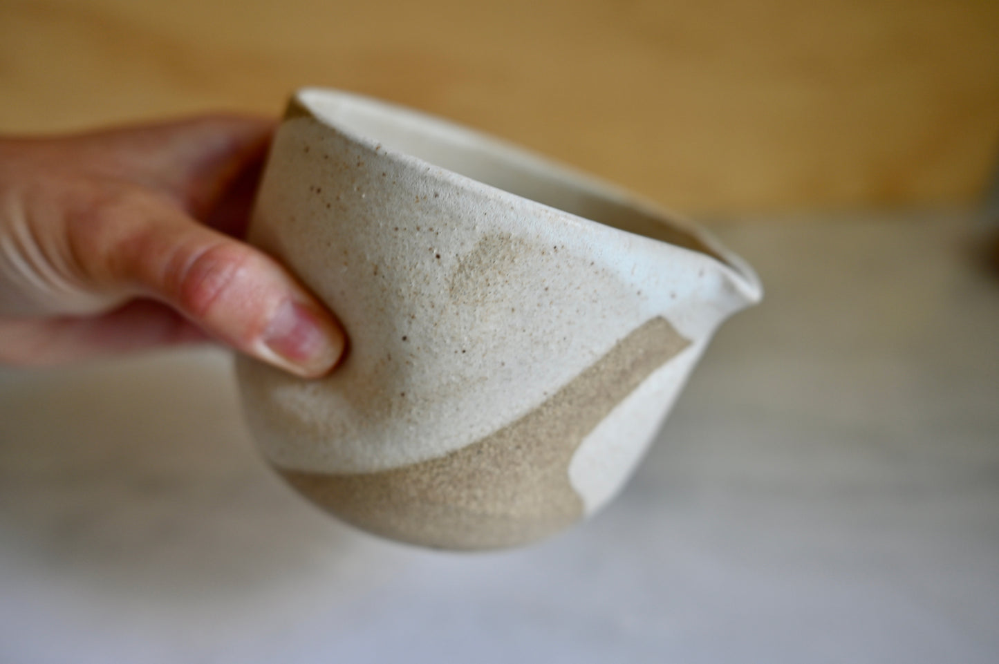 Person holding a matcha bowl glazed in white with dimples on the side